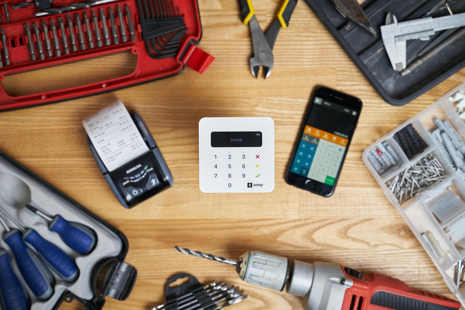 Tools and payment processing equipment on a wooden surface, suggesting a construction business.