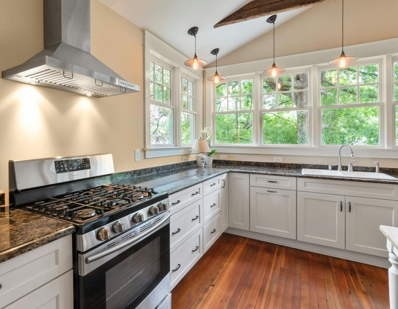 Modern kitchen with white cabinets, stainless steel appliances, and dark countertops.