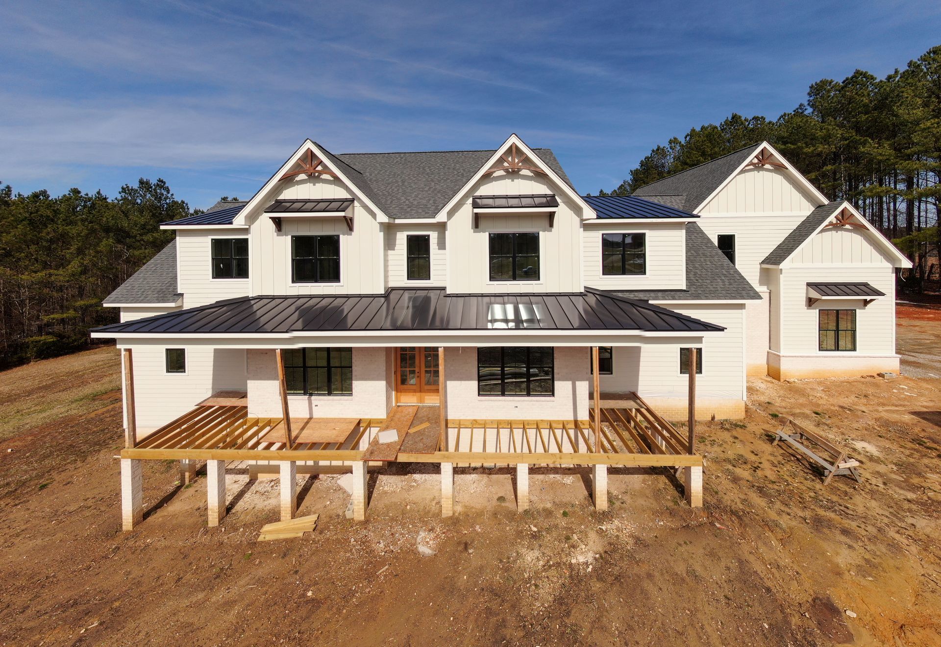 Large modern residence under custom home construction, featuring a partially built rear deck and unfinished landscaping.