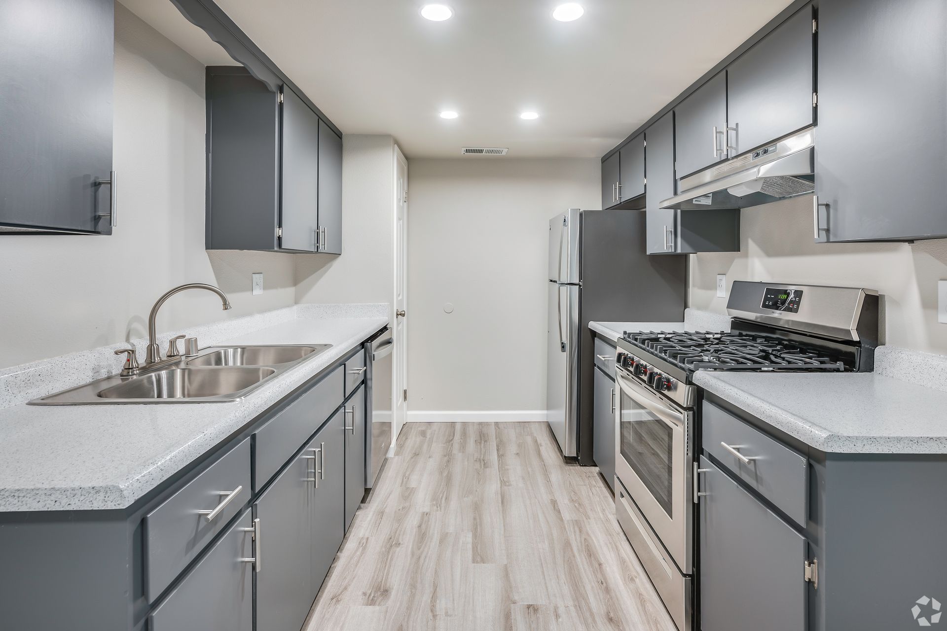 Gray and white galley kitchen with stainless steel appliances.