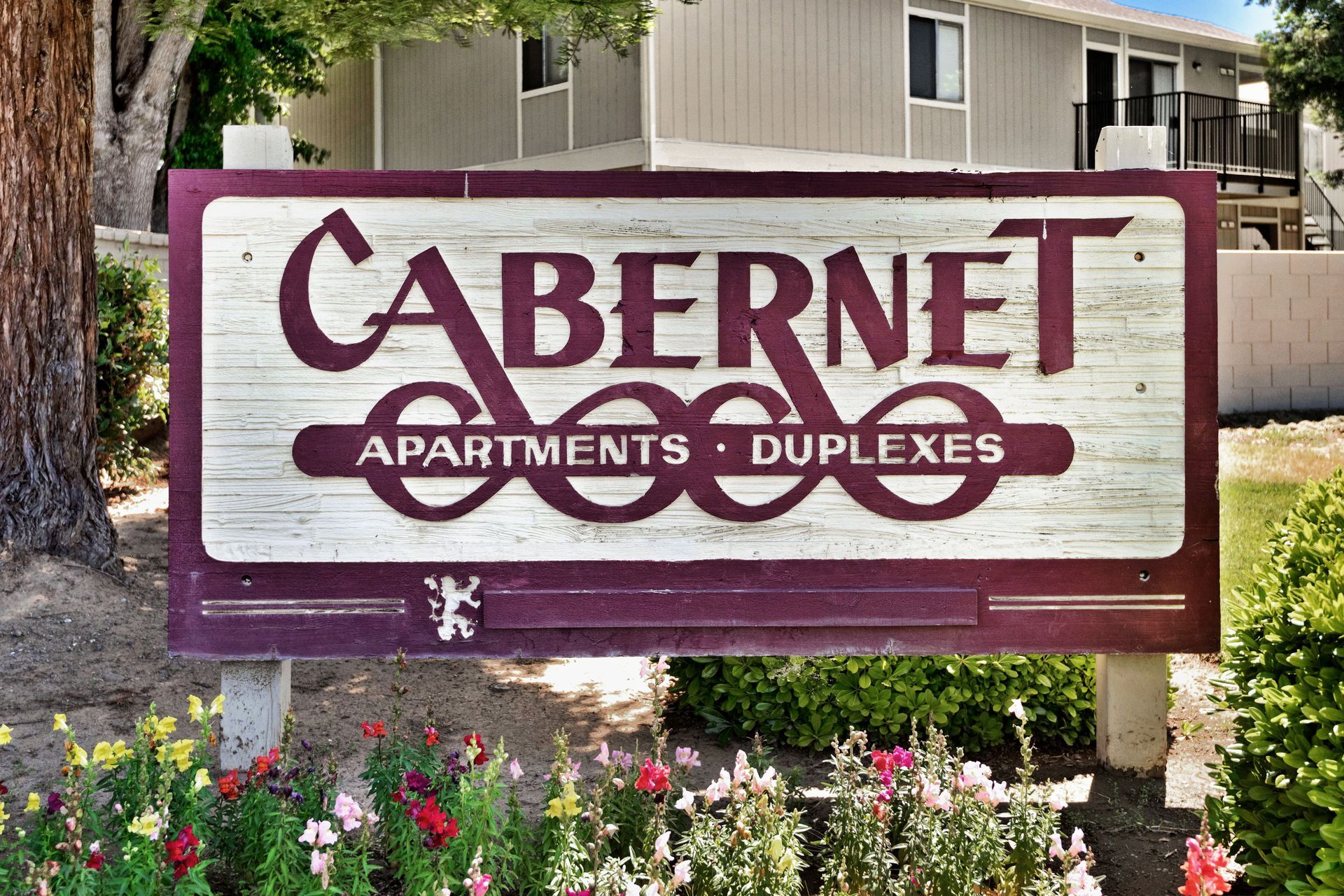 Sign for Cabernet Apartments and Duplexes with maroon and white lettering.