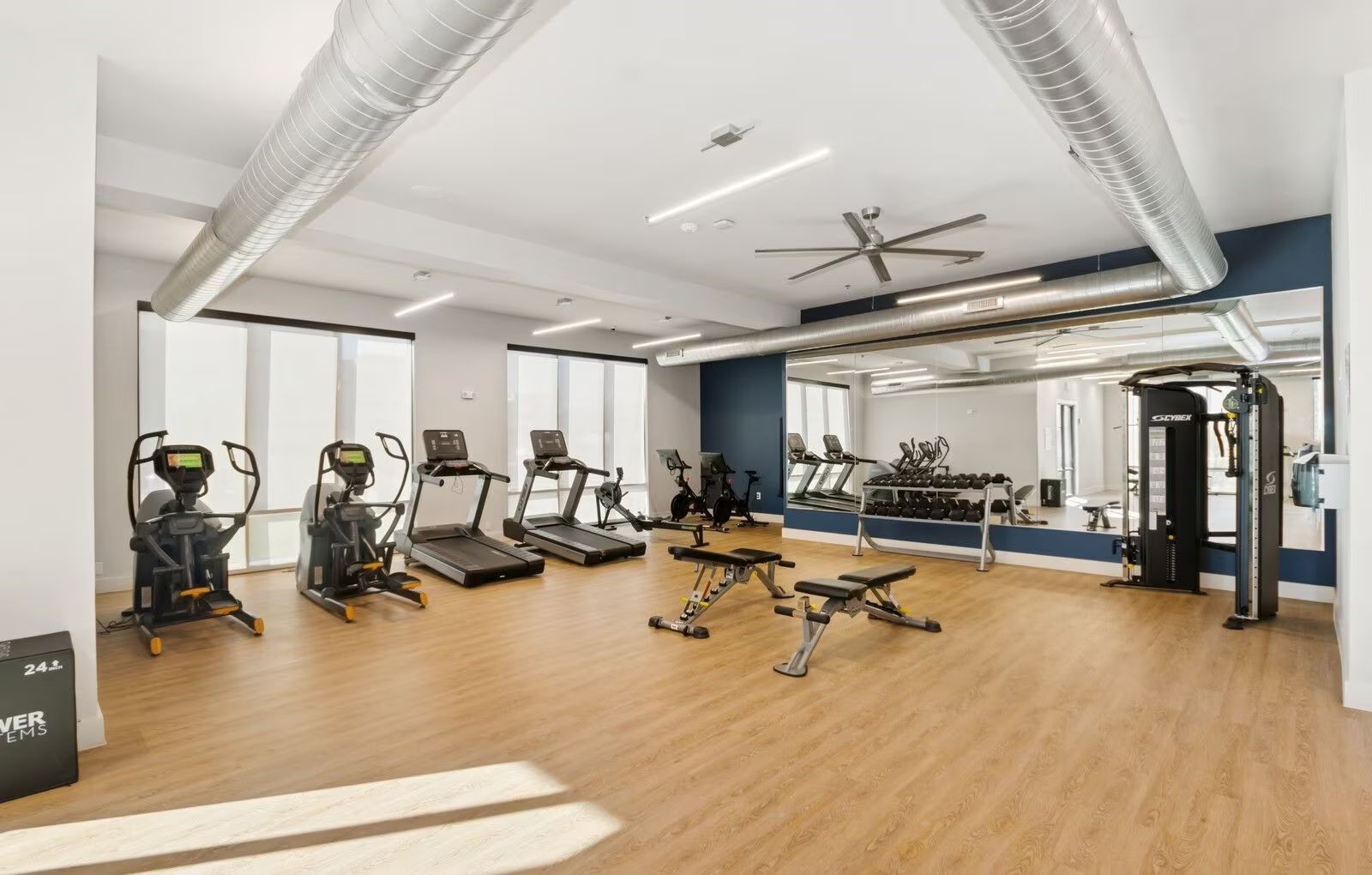 Gym interior with exercise machines, weights, and large mirror.