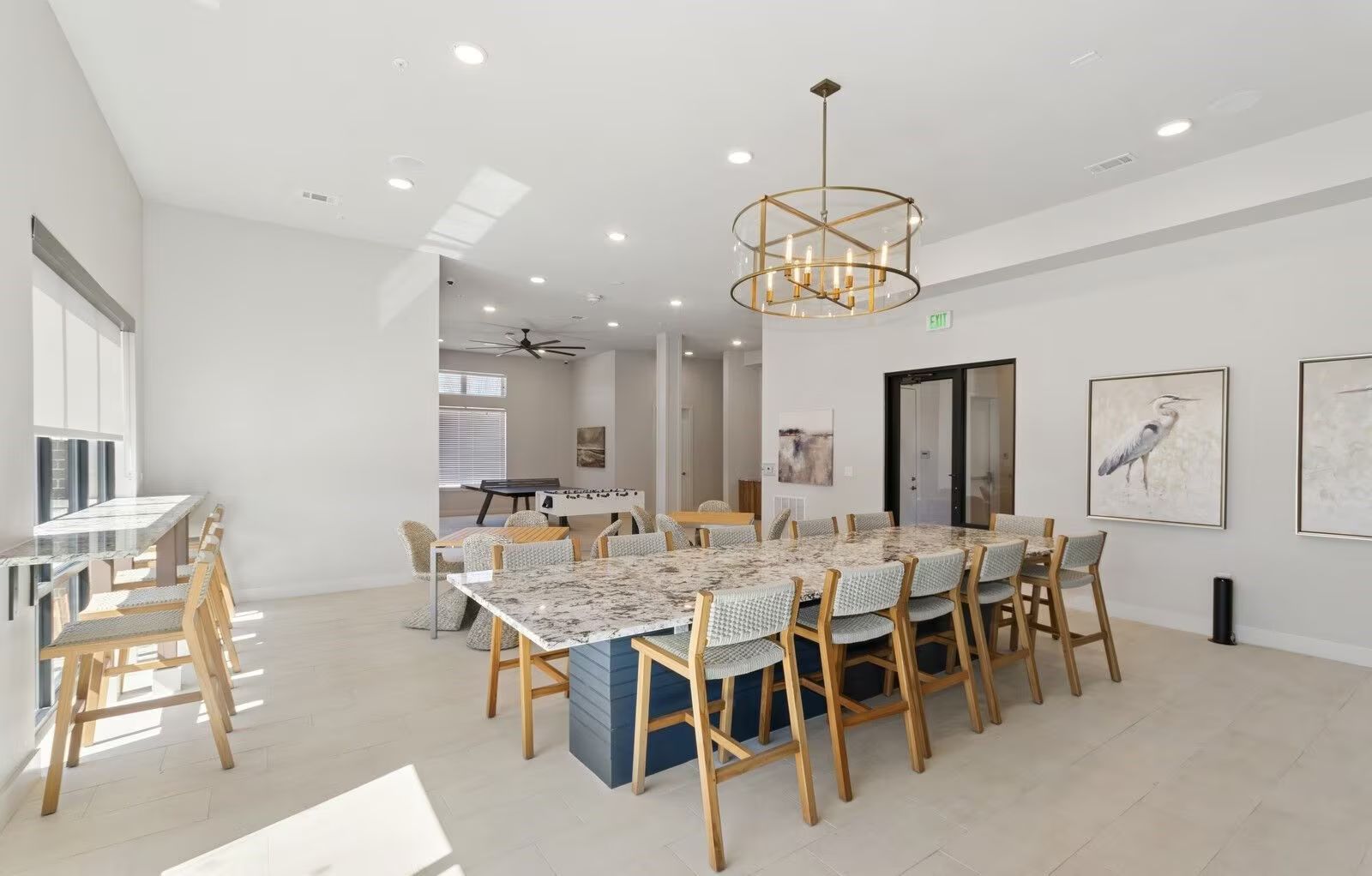 Bright, modern community room with long table and chairs, pendant light, and artwork.