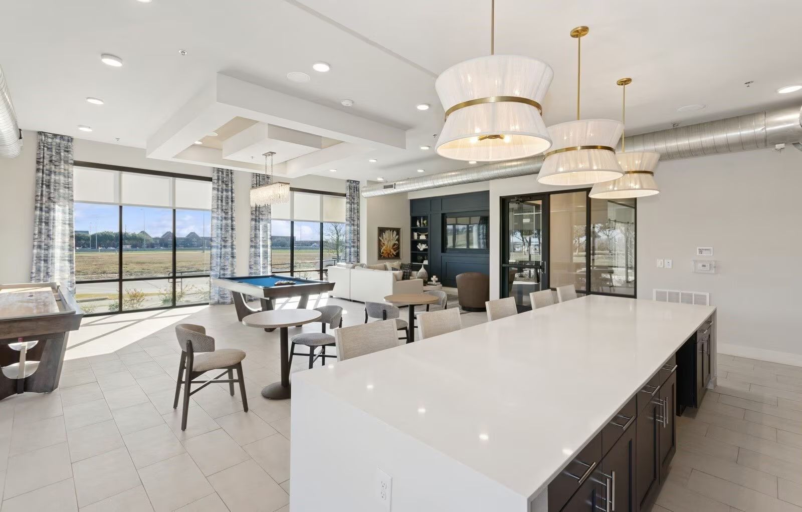 Spacious modern lounge area with a pool table, bar, and large windows.