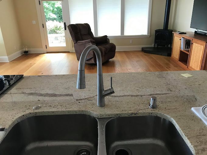 A kitchen sink with a faucet and a chair in the background