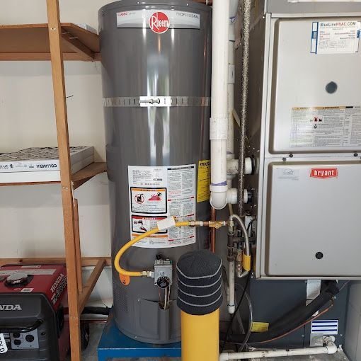 A gray water heater is sitting in a room next to an air conditioner.