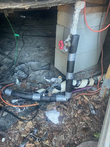 A bunch of pipes are laying on the ground in a basement.