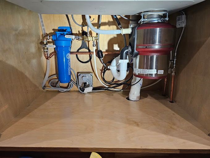 A kitchen sink with a water filter and a garbage disposal underneath it.