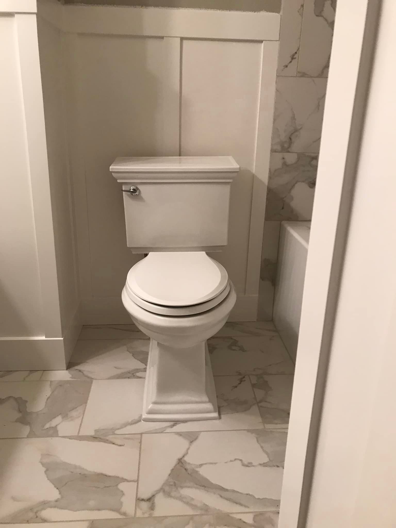 A white toilet is sitting in a bathroom next to a bathtub.