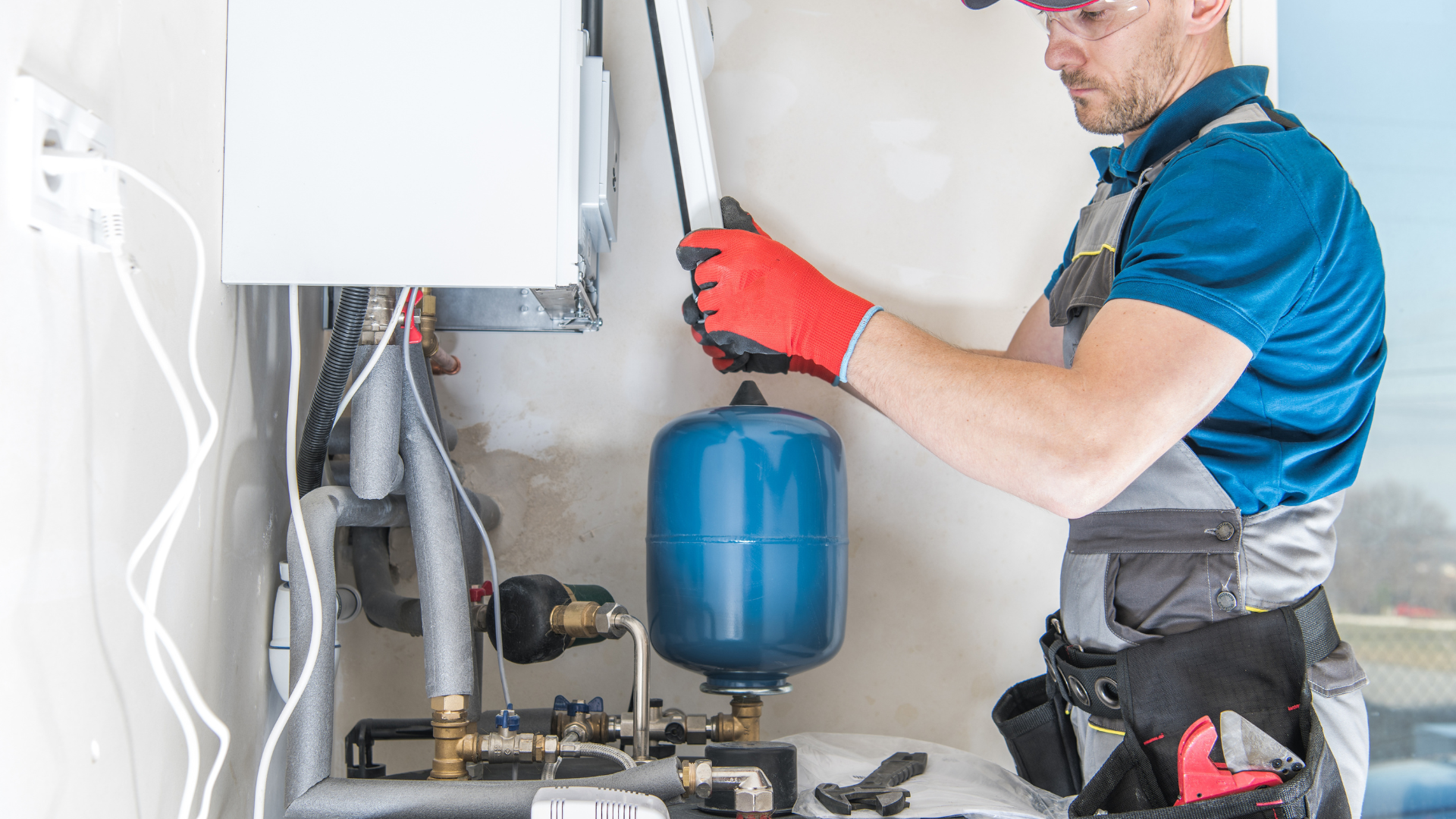 A man is working on a boiler in a room.