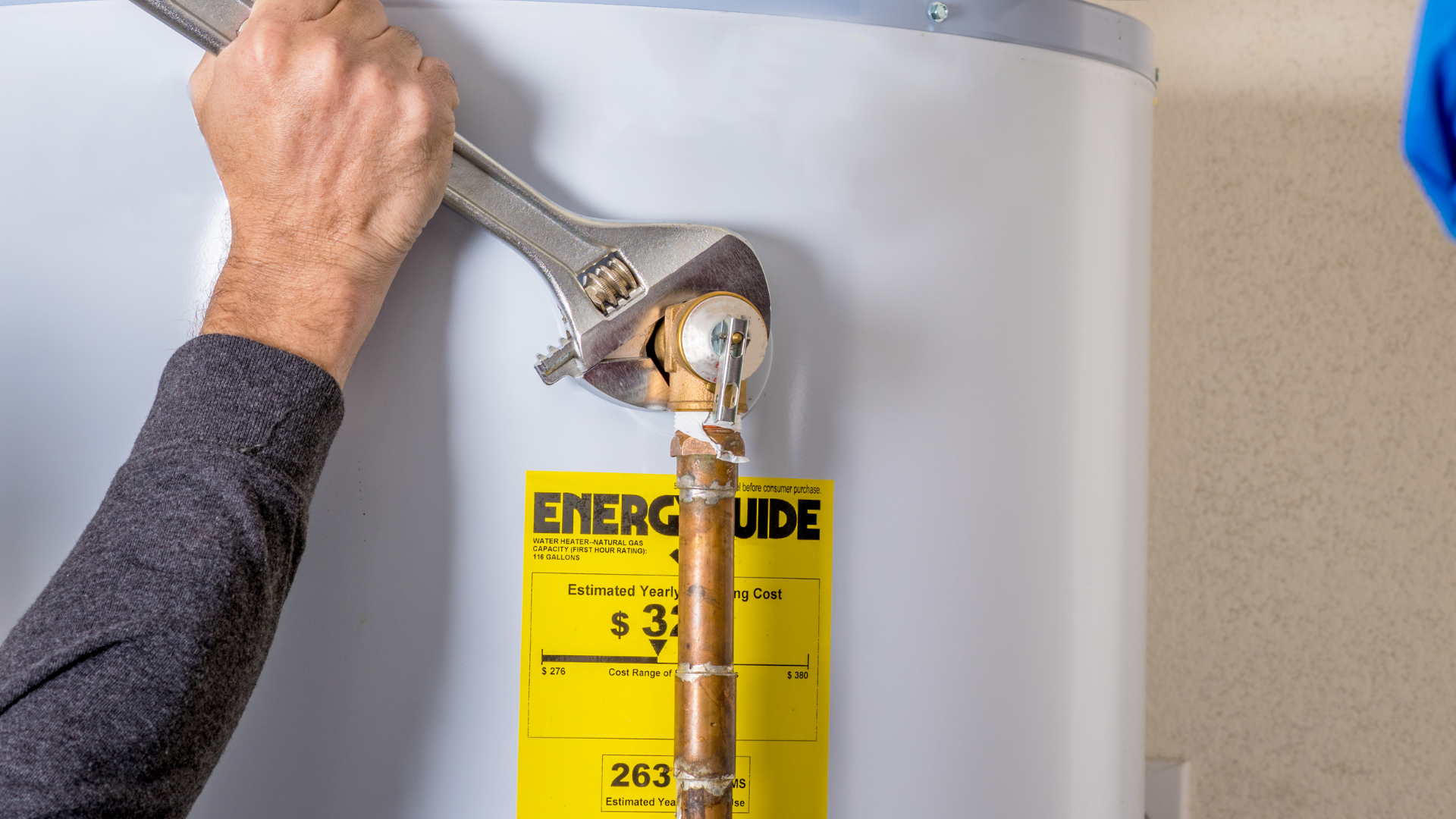 A man is fixing a water heater with a wrench.