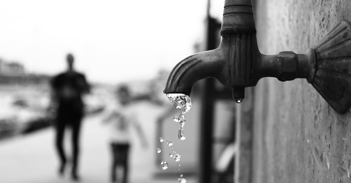 A black and white photo of a faucet with water dripping from it.