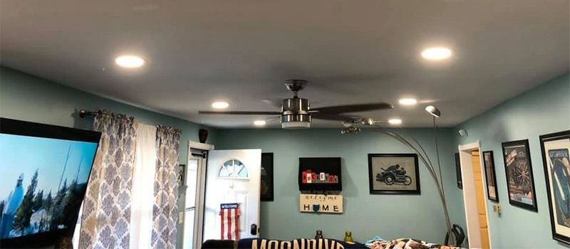 A living room with a ceiling fan and a flat screen tv.