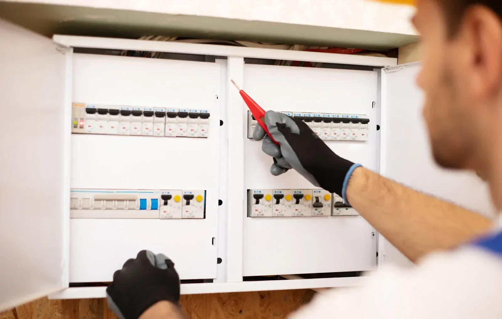 Electrician using a voltage tester on a circuit breaker panel.