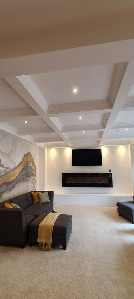 A living room with a couch , ottoman , fireplace and television.