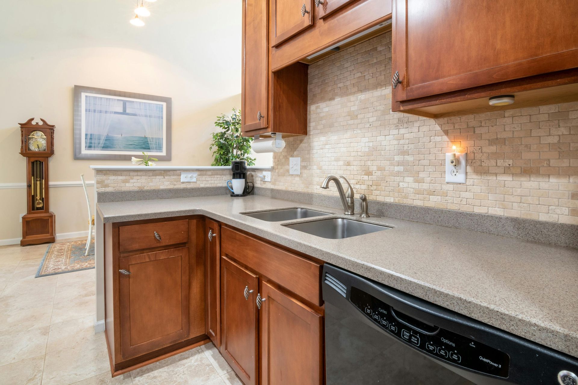 A kitchen with wooden cabinets , granite counter tops , a sink and a dishwasher.