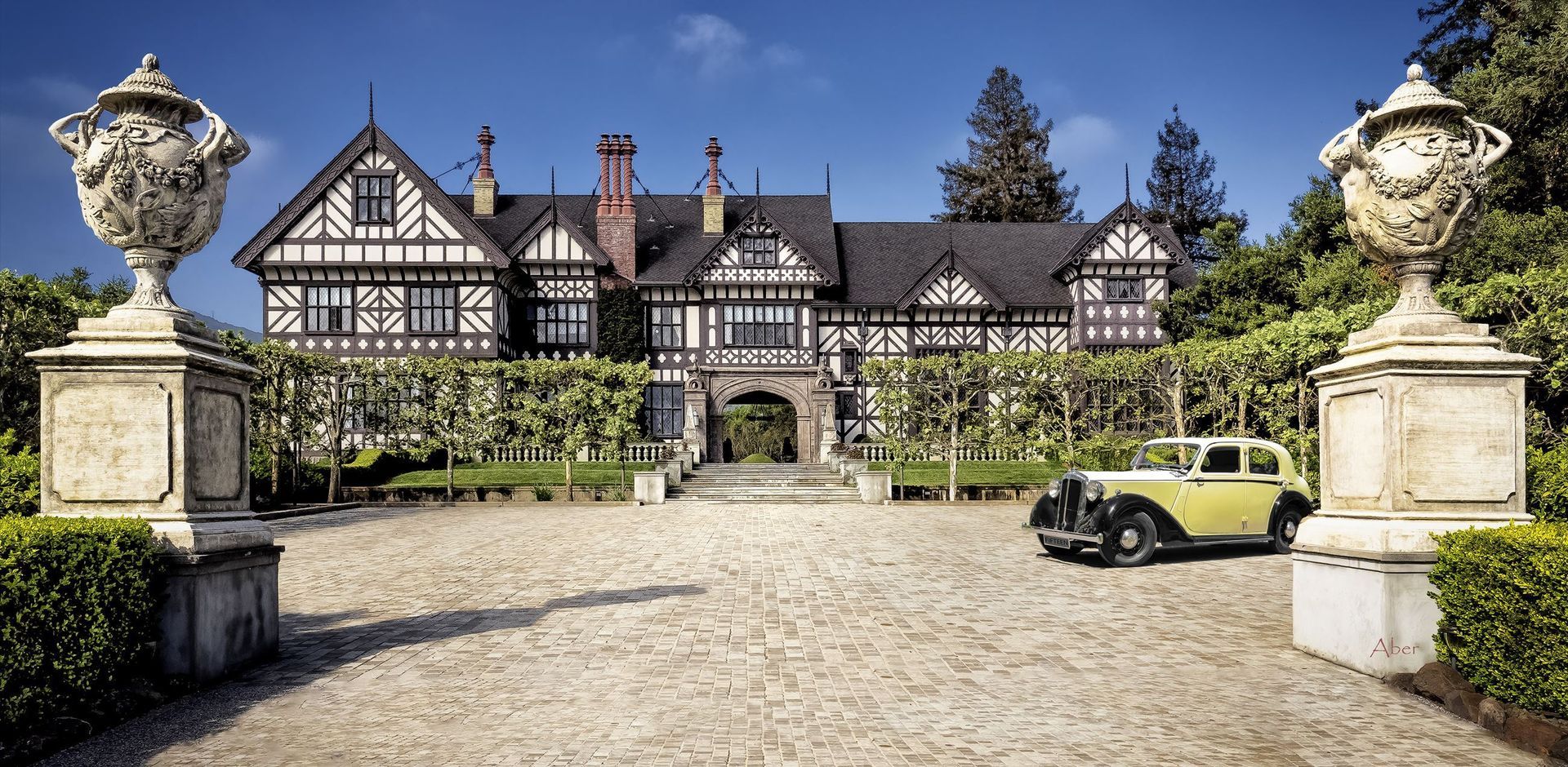 A yellow car is parked in front of a large house