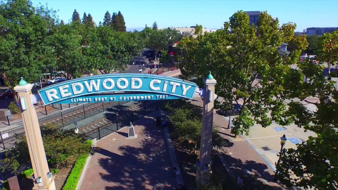 An aerial view of a sign for redwood city surrounded by trees.