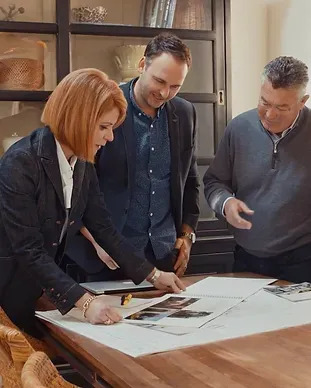 A group of people are sitting around a table looking at a piece of paper.