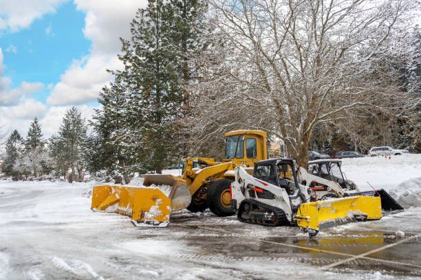 A couple of snow plows are parked in a parking lot.