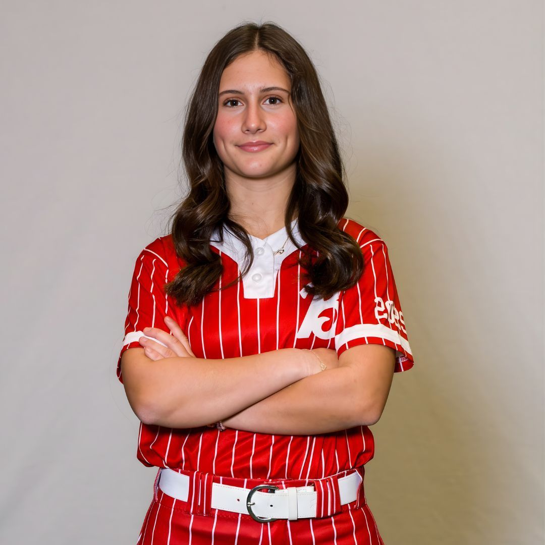 A person wearing a red and white pinstriped athletic uniform with arms crossed, posing against a neutral gray background.