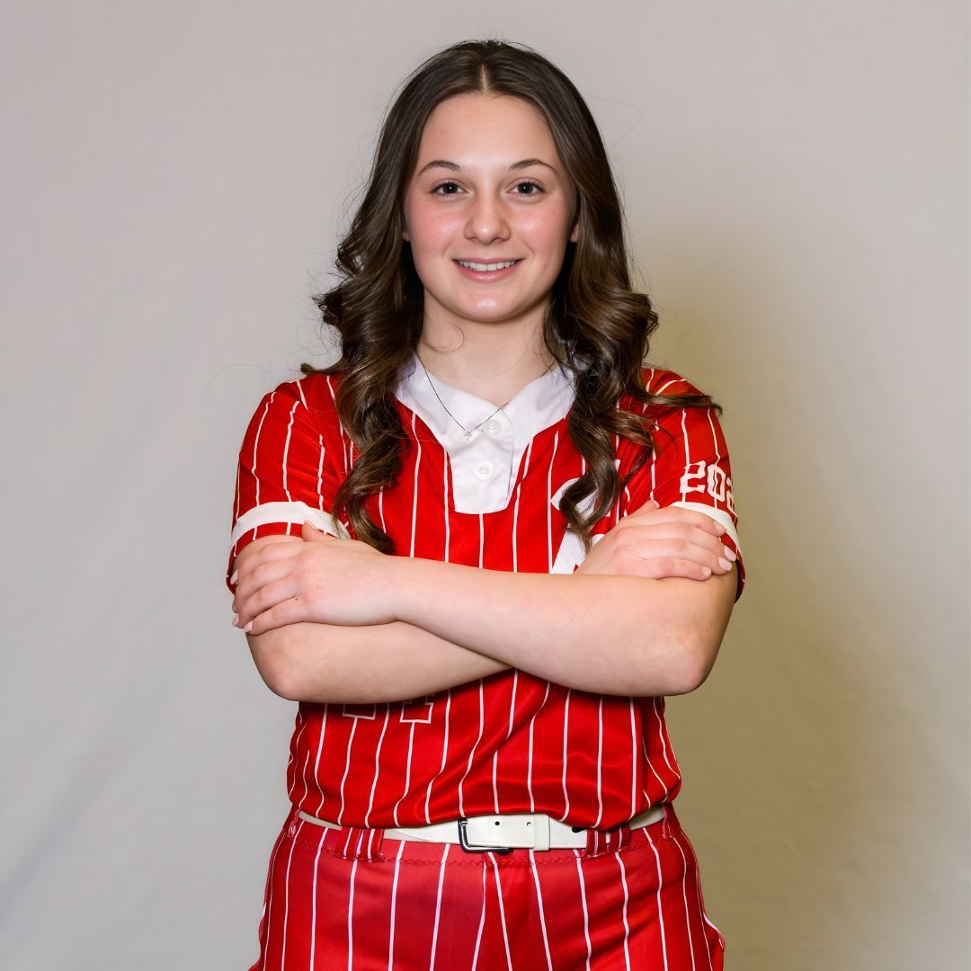 A person wearing a red and white striped athletic uniform with arms crossed, posing against a plain light gray background.