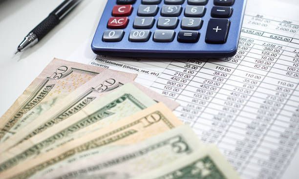 Money and calculator on a spreadsheet; a pen lies nearby.