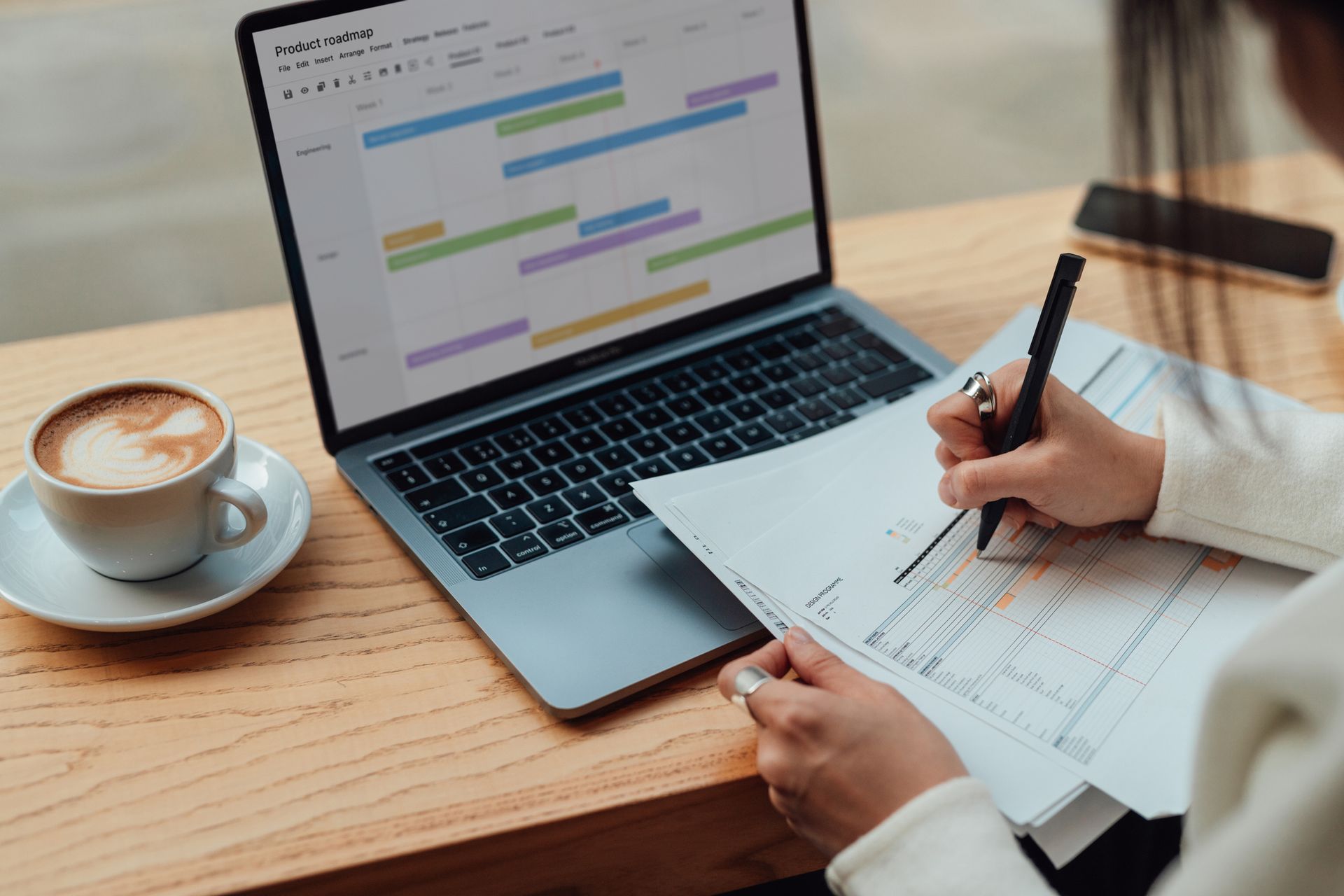 Tax planning professional reviewing financial papers beside laptop displaying project timeline.