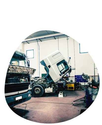 Truck repair shop: one truck with the hood open, another on the left, both inside a garage.
