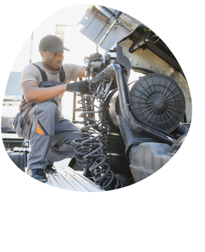 Mechanic working on the engine of a truck outdoors.
