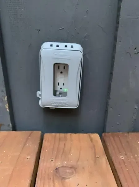 A white electrical outlet is sitting on a wooden table.