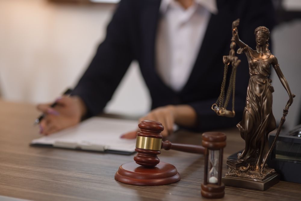 A judge is sitting at a desk with a statue of justice and a wooden gavel.