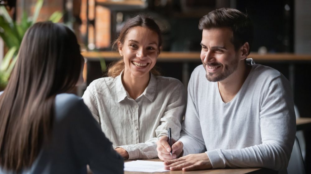 A man and a woman are sitting at a table signing a document.