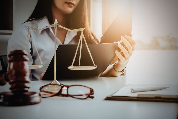 A woman is sitting at a table with a scale of justice and a judge 's gavel.