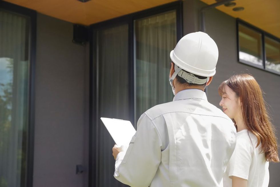 A person is shaking hands with a real estate agent in front of a model house.