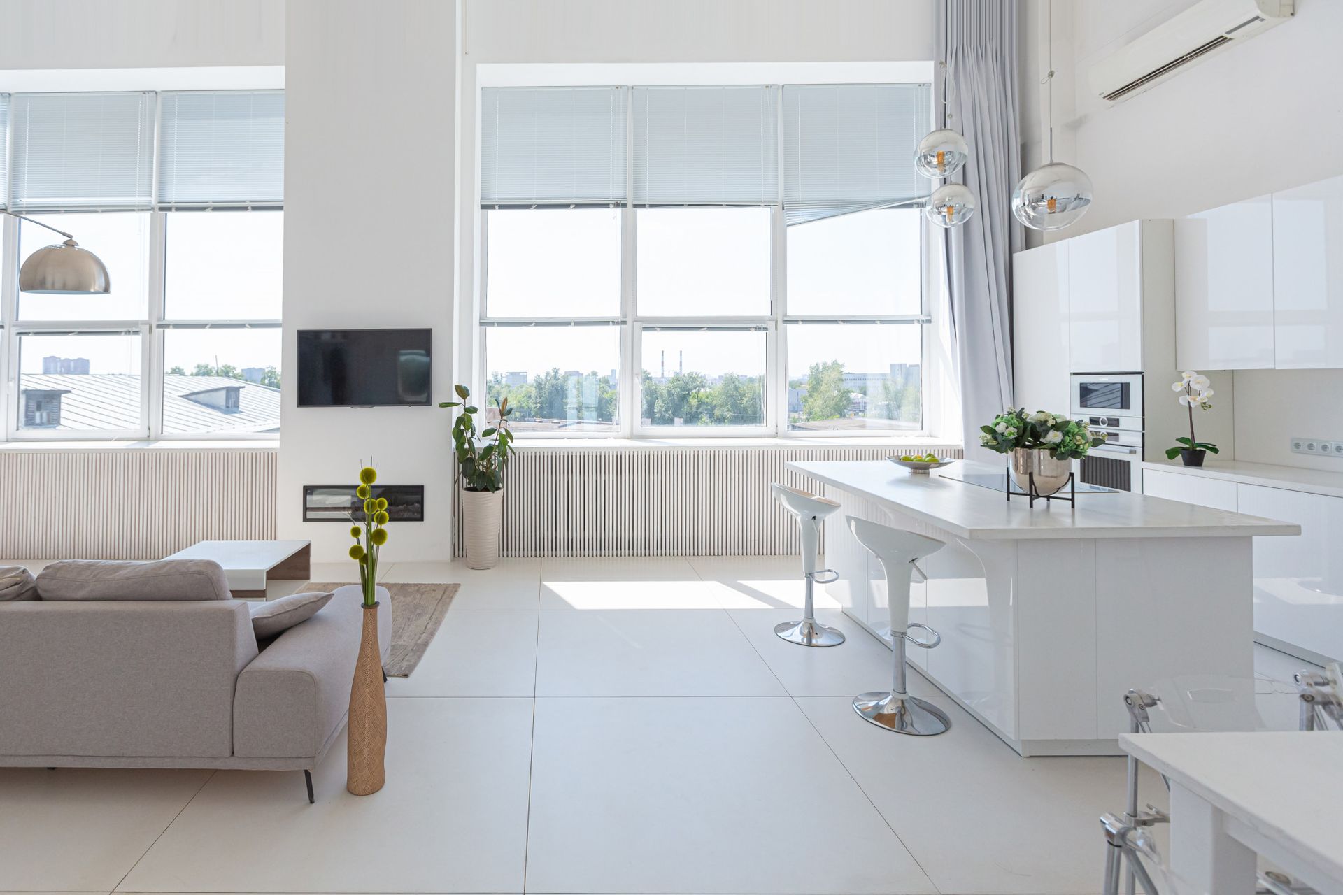 A living room with a couch and a kitchen with a lot of windows.
