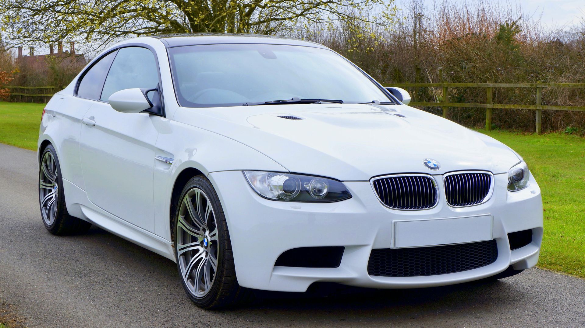 A white bmw m3 is parked on the side of a road.