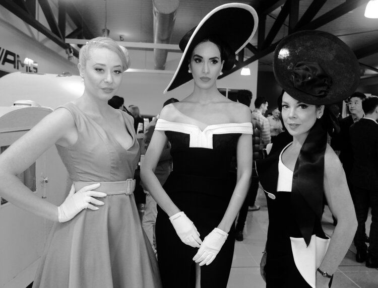 Three women standing next to each other wearing hats and gloves