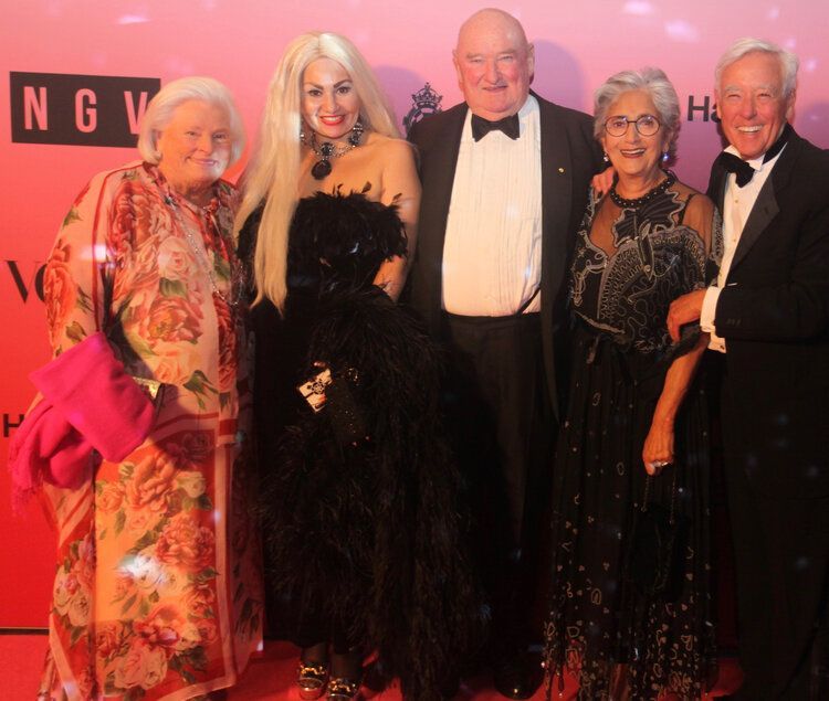 A group of people posing for a picture in front of a wall that says ngv