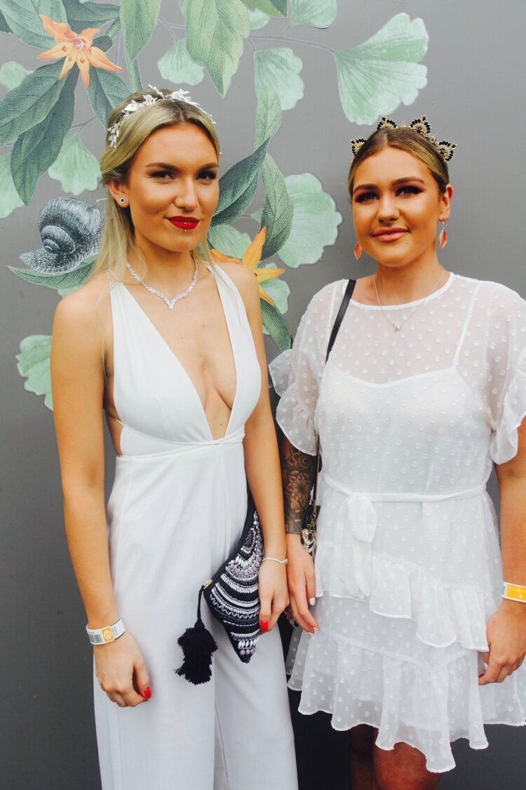 Two women in white dresses are posing for a picture.