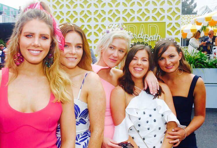 A group of women are posing for a picture in front of a sign that says rad