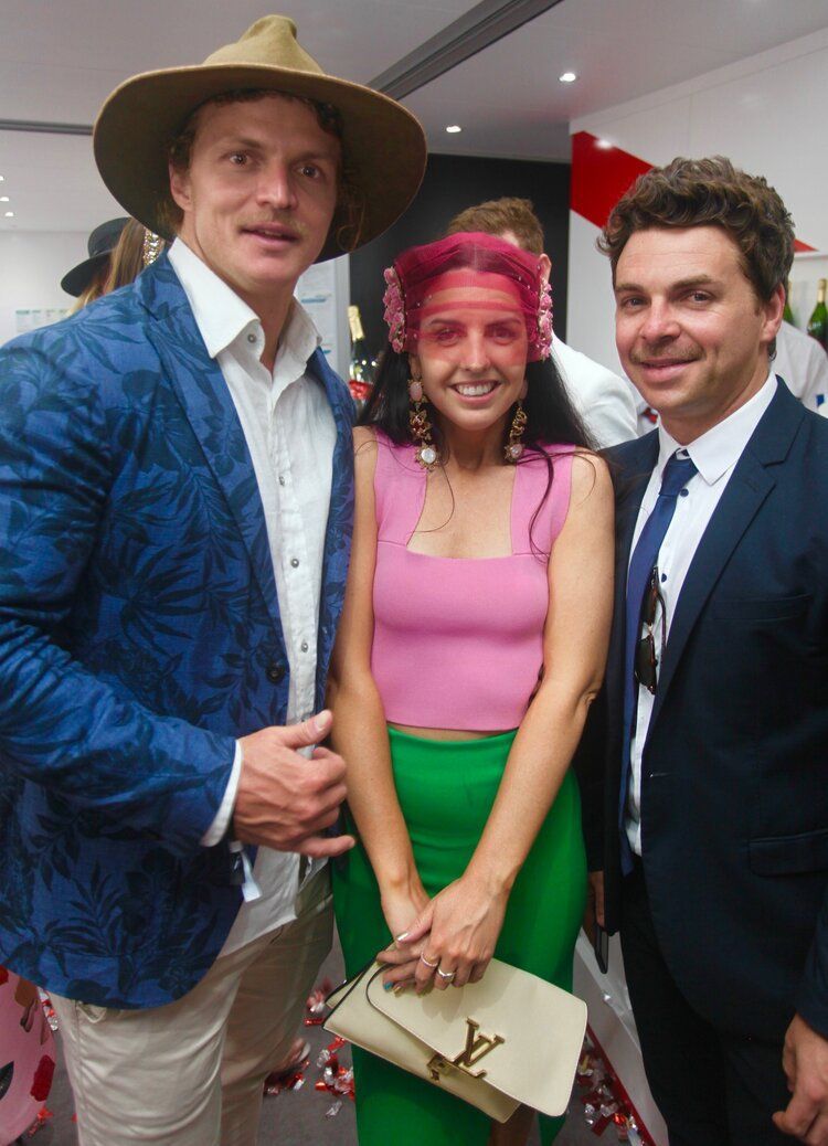 A man in a blue jacket is standing next to a woman in a pink top and green skirt