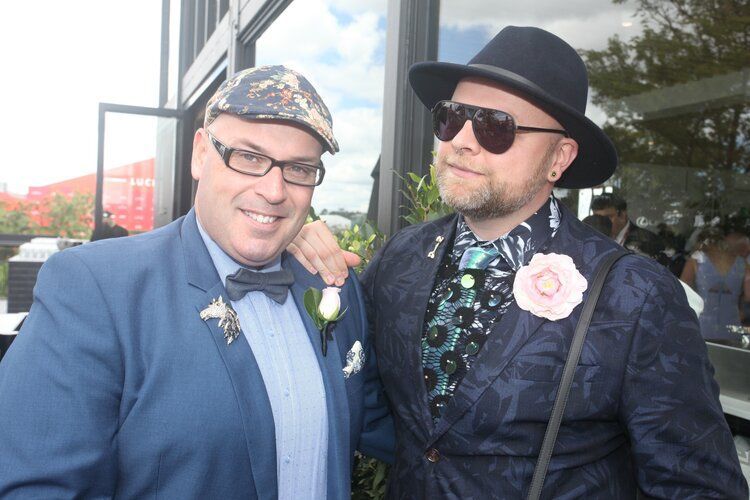 Two men in suits and hats are posing for a picture.