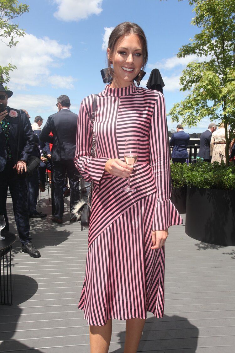 A woman in a striped dress is holding a glass of wine.