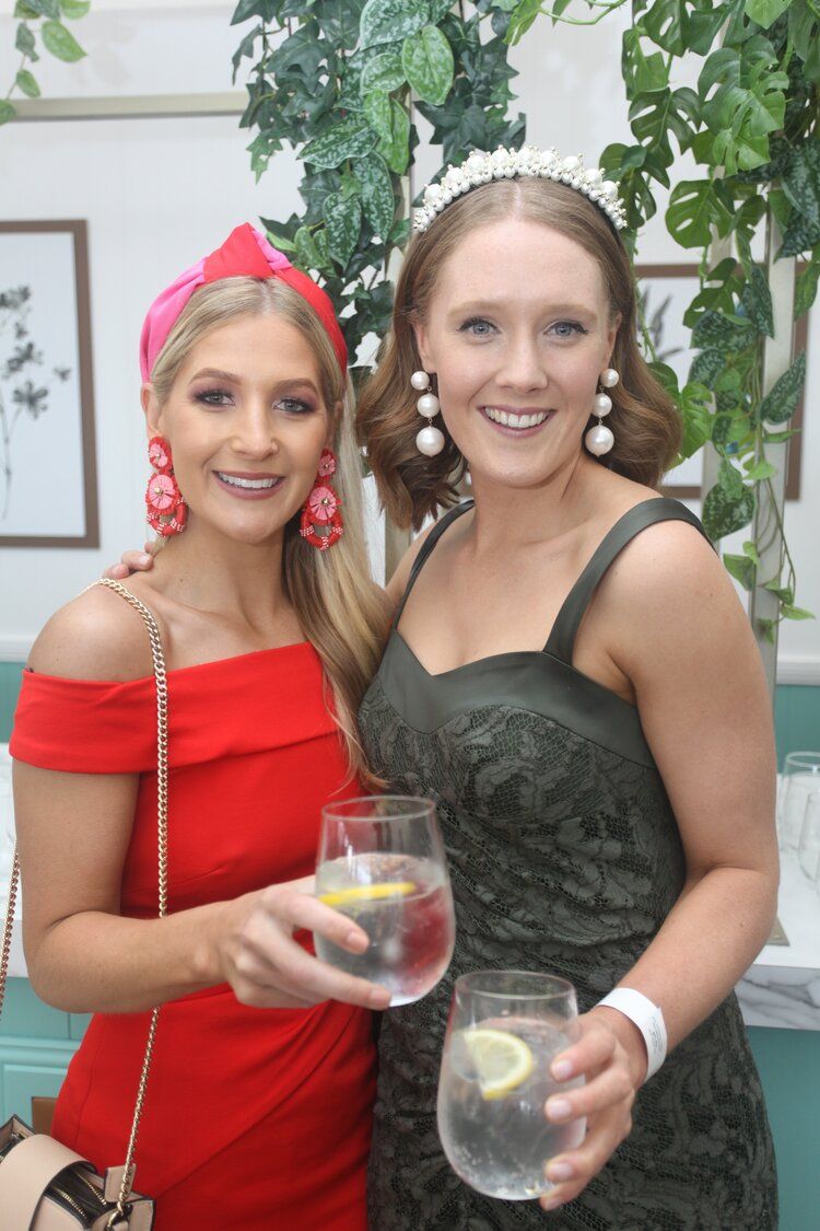 Two women are posing for a picture while holding glasses of water.