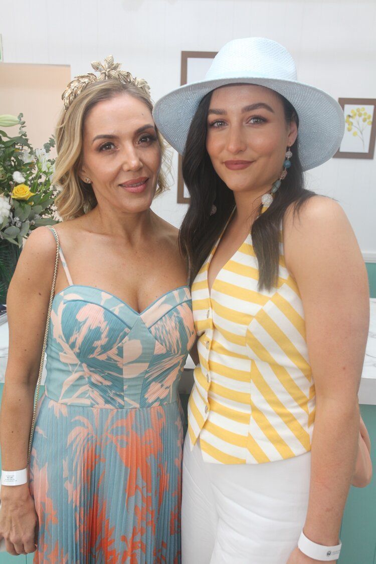Two women are posing for a picture together and one of them is wearing a hat.
