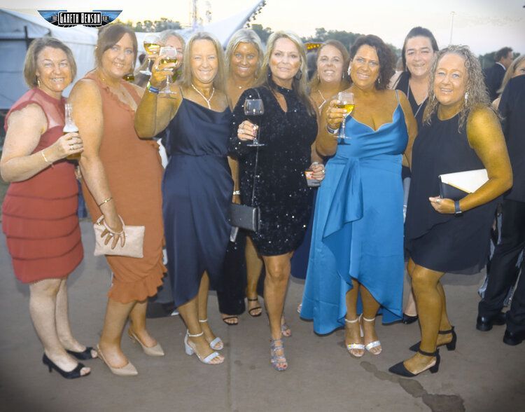 A group of women standing next to each other holding wine glasses