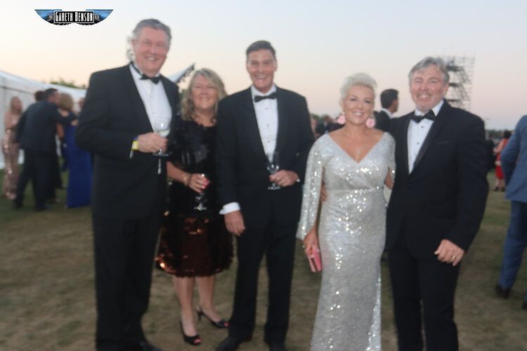 A group of people in tuxedos pose for a picture