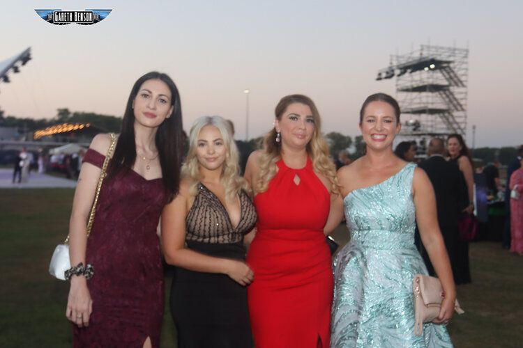 A group of women posing for a picture with one wearing a red dress