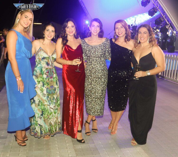 A group of women are posing for a picture and one of them is wearing a blue dress